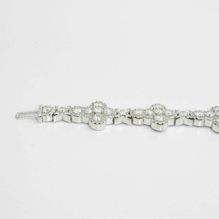 The Moissanite Cross Fancy Bracelet, crafted from 925 sterling silver and adorned with round, sparkling gemstones in floral-inspired patterns, is displayed against a plain white background.