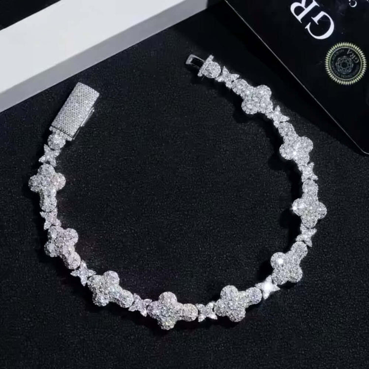 The Moissanite Cross Fancy Bracelet, crafted from 925 sterling silver and adorned with sparkling gems, is displayed on a black textured surface next to a partially visible black card.