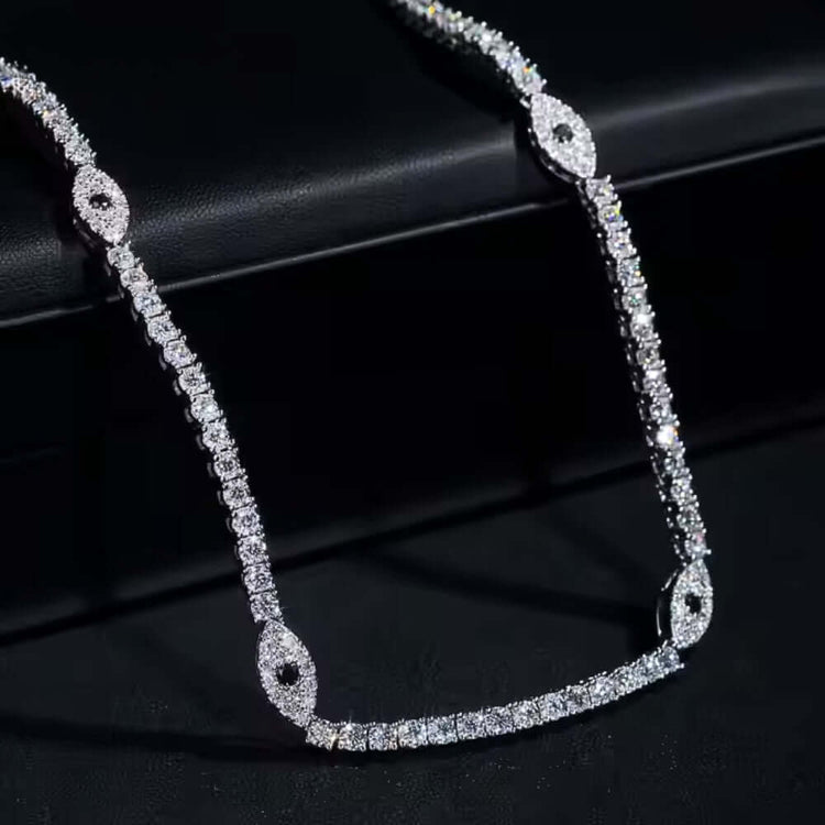 The Evil Eye Tennis Chain - 3mm features oval diamond clusters set along a chain of round diamonds and is beautifully displayed on a black surface.