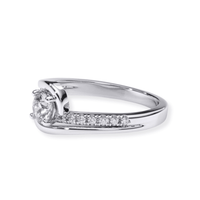 The Swirl Pavé Round-Cut Lab Diamond Engagement Ring features a round lab diamond in a modern bypass design with pavé accents along one side of the white gold band.