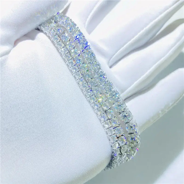 A close-up of a white glove with sparkling rhinestones in three rows, reflecting colorful light, evokes the shimmering elegance of the Tennis Bracelet - 14k Gold Moissanite.