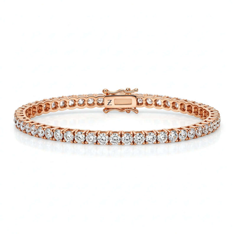 The Tennis Bracelet - 14k Gold Natural Diamonds features a single row of round white diamonds set in prongs on rose gold with a secure clasp, shown against a white background—an elegant luxury jewelry piece.