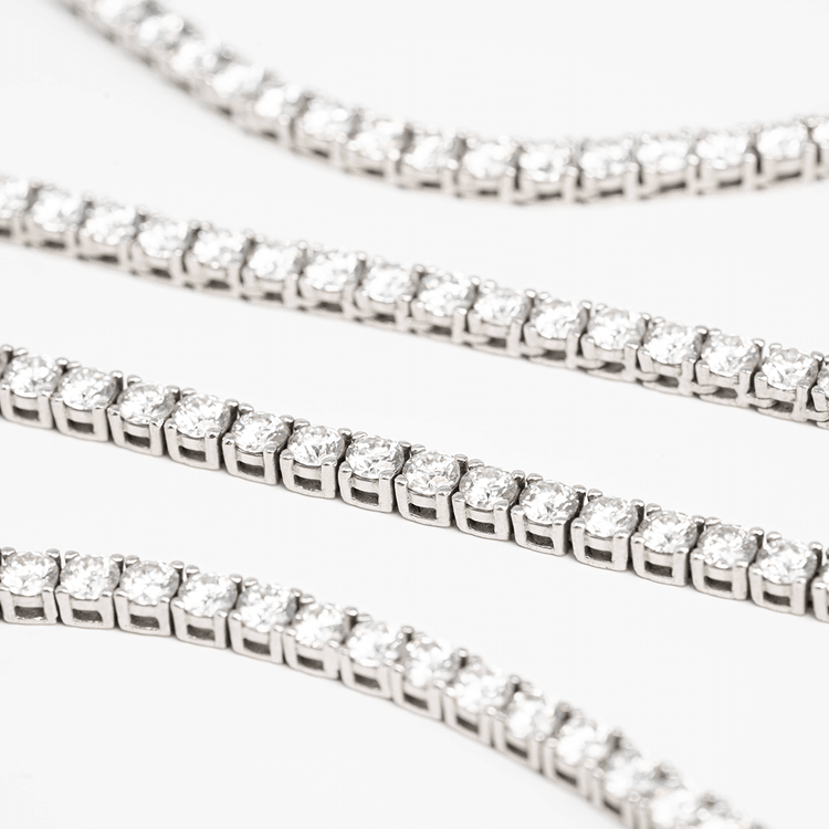 Tennis Bracelet - 925 Silver Moissanite bracelets featuring brilliant round stones are displayed diagonally on a white background, highlighting their sparkle and the shine of sterling silver links.