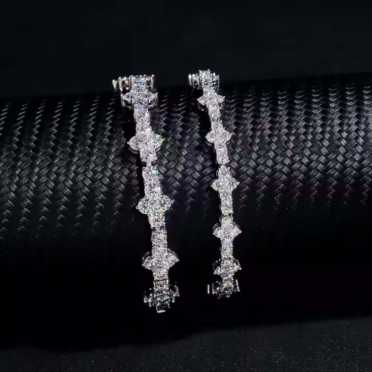 A pair of sparkling diamond hoop earrings displayed on a textured black surface, featuring geometric diamond patterns—perfect for pairing with the Tiny Cross Diamond Bracelet in 925 sterling silver for added elegance.
