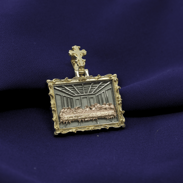The Tricolor Last Supper Pendant – 14K Gold Men Pendant, featuring a detailed relief in an ornate rectangular frame with a cross, is displayed elegantly on deep purple fabric.