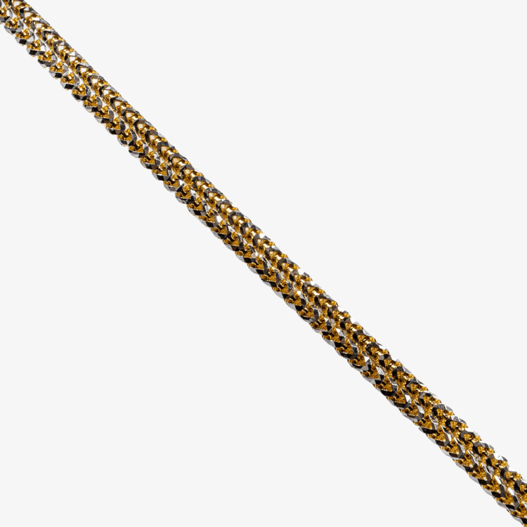 A close-up of the Franco Chain Two Tone Prism Cut bracelet, 3mm in 10k solid gold, displayed diagonally on a white background. Its detailed intertwined design alternates gold and silver tones for a striking look.