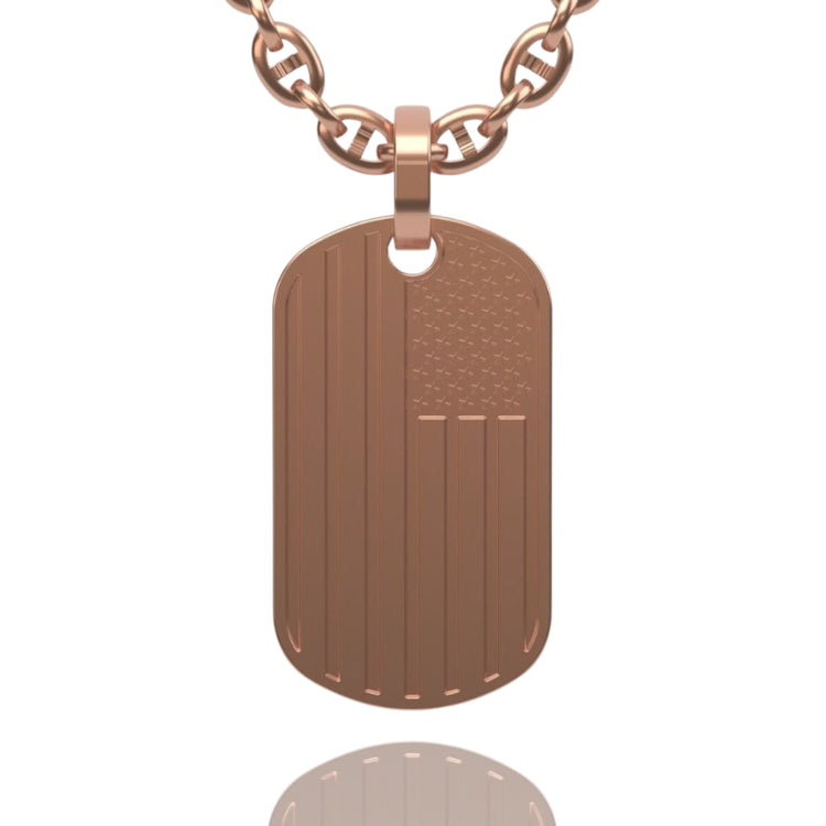 The USA Flag Tag Pendant is a rose gold dog tag necklace featuring an engraved American flag design, displayed on a white background with its reflection below.