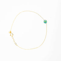 The one lucky eye bracelet - 14k features a delicate 14k gold chain with a blue, white, and black enamel evil eye charm for spiritual protection. It has an adjustable clasp and is shown on a white background.