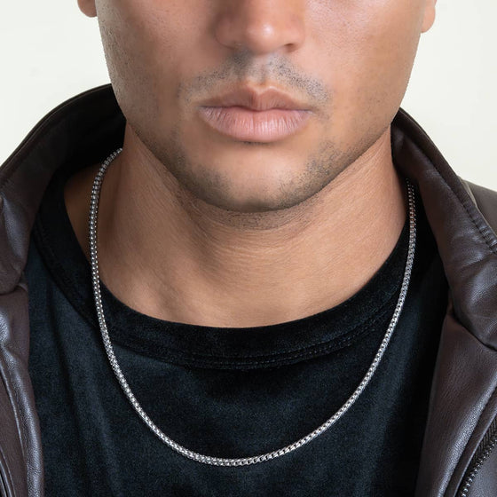 Man wearing 10K white gold Franco chain with sleek modern design, adding elegance to a casual black shirt and leather jacket ensemble.