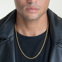 Wearing a black textured shirt, black leather jacket, and a Franco Chain- 1.8mm-6.5mm Solid Yellow Gold necklace, the image is cropped to reveal only the lower face, neck, and upper chest.