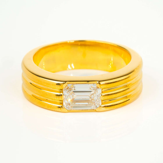 The sleek, polished band enhances the brilliance of the emerald-cut stone, creating a timeless and refined look.