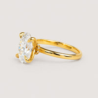 A 1.72ct oval-cut lab diamond engagement ring in 14k solid yellow gold with a prong setting, displayed on a warm off-white studio background.