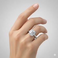 A hand with manicured nails displays the Emerald-Cut Halo Lab Diamond Engagement Ring with Pavé Band and a matching diamond wedding band against a plain light gray background.
