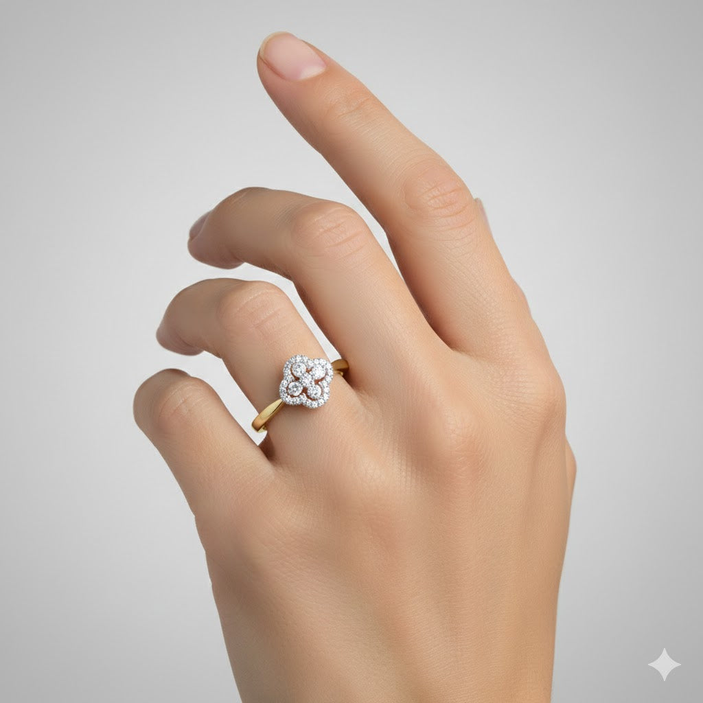 A hand with manicured nails wears the 10k White & Rose Gold Diamond Clover Ring 1/4 Cttw, featuring a clover design with sparkling diamonds, set against a plain light gray background.