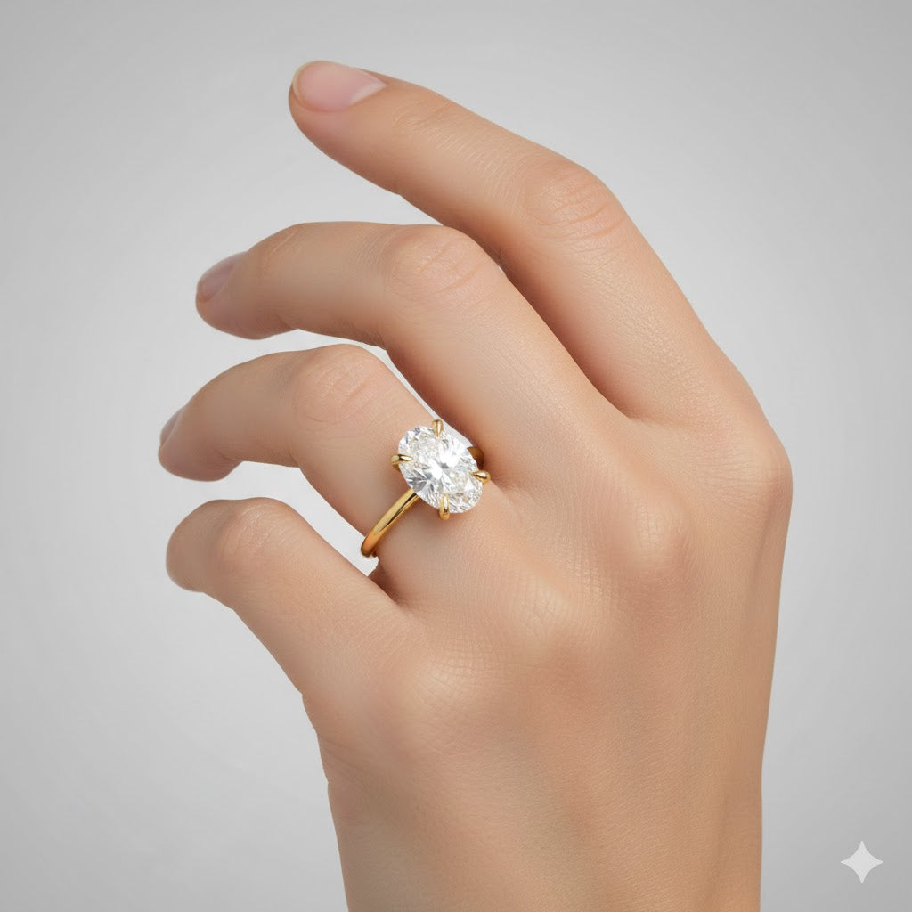 A hand with neatly manicured light pink nails wears the 1.72ct Oval-Cut Lab Diamond Engagement Ring in 14k solid yellow gold, featuring a large oval diamond, against a plain light gray background.