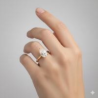 A hand with neatly groomed nails wears the 2.08ct Pear Lab Diamond Solitaire Engagement Ring in 14K yellow gold, featuring a stunning pear-cut lab-grown diamond against a plain light gray background.