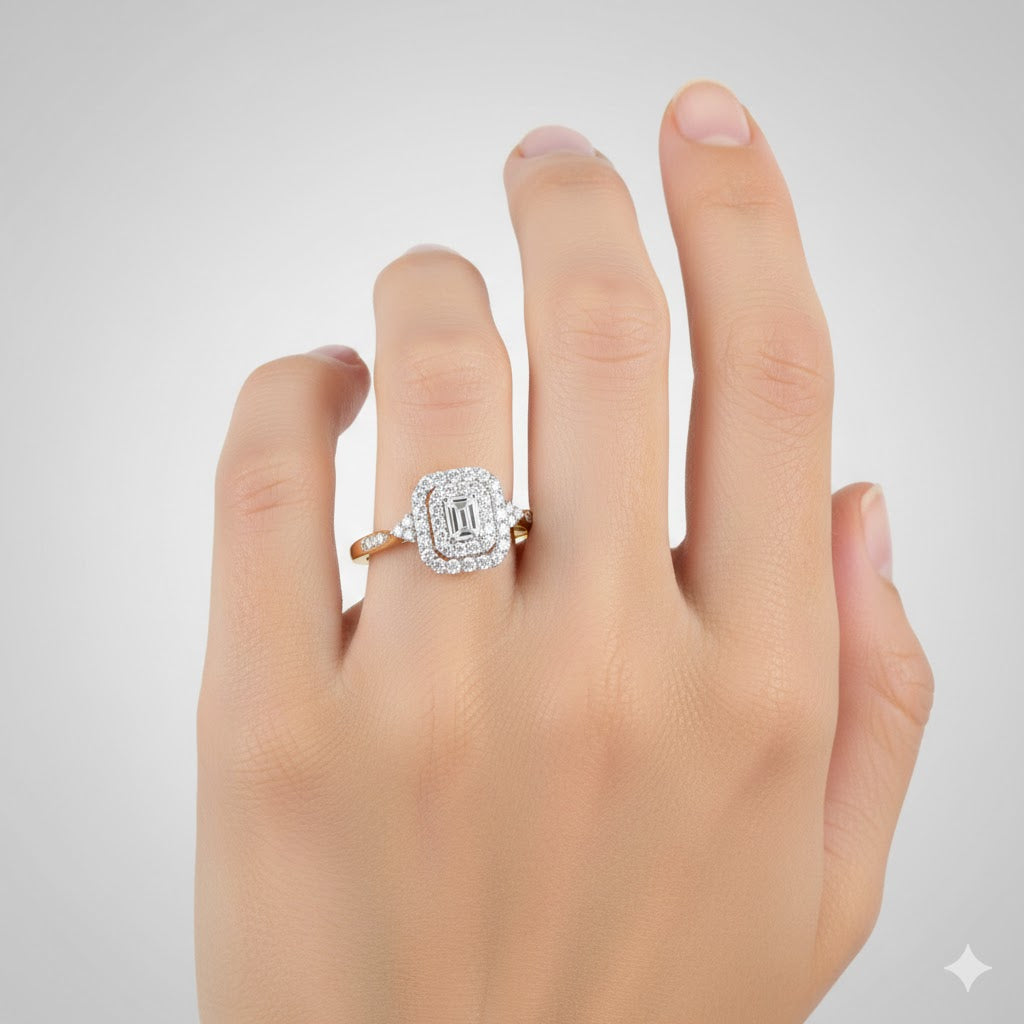 A hand with a light skin tone wears the 1/3CTW Diamond Emerald Double Halo Engagement Ring in 14k gold, featuring a large rectangular center stone and natural diamonds, set against a plain light gray background.