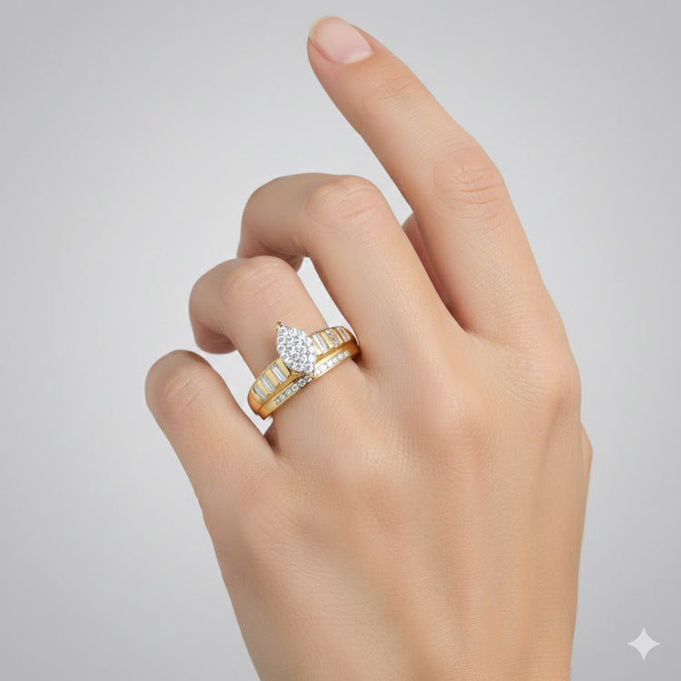 A hand with a light skin tone is shown against a gray background, wearing the 10k Gold Oval Diamond Cluster Bridal Ring 1/2 Cttw. The ring features an oval diamond cluster and baguette-cut diamonds on the band; the middle and pointer fingers are slightly raised.