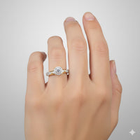 A hand with neatly manicured nails wears the 1/3CTW Diamond Round Single Halo Engagement Ring in 10k gold, featuring a round center stone surrounded by diamonds, paired with a matching band against a light gray background.