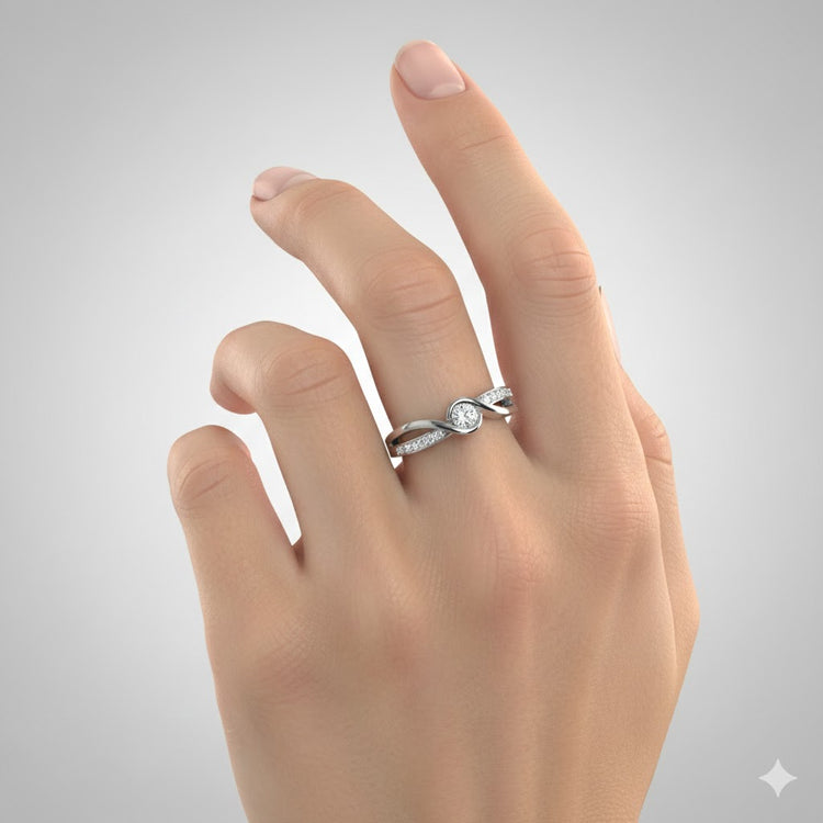 A hand with manicured nails showcases the Engagement Twist Ring - Lab Diamond, a silver ring featuring a round lab-grown diamond and side stones in a delicate twisted design, set against a plain gray background.