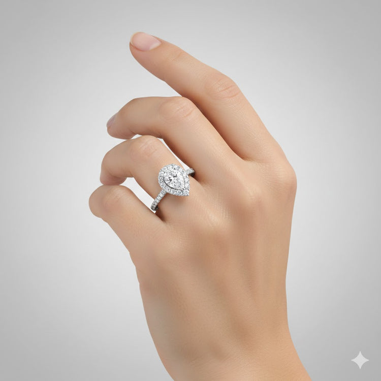A hand wearing the Pear-Shaped Halo Lab Diamond Engagement Ring with Pavé Band on the ring finger, shown against a plain light gray background.