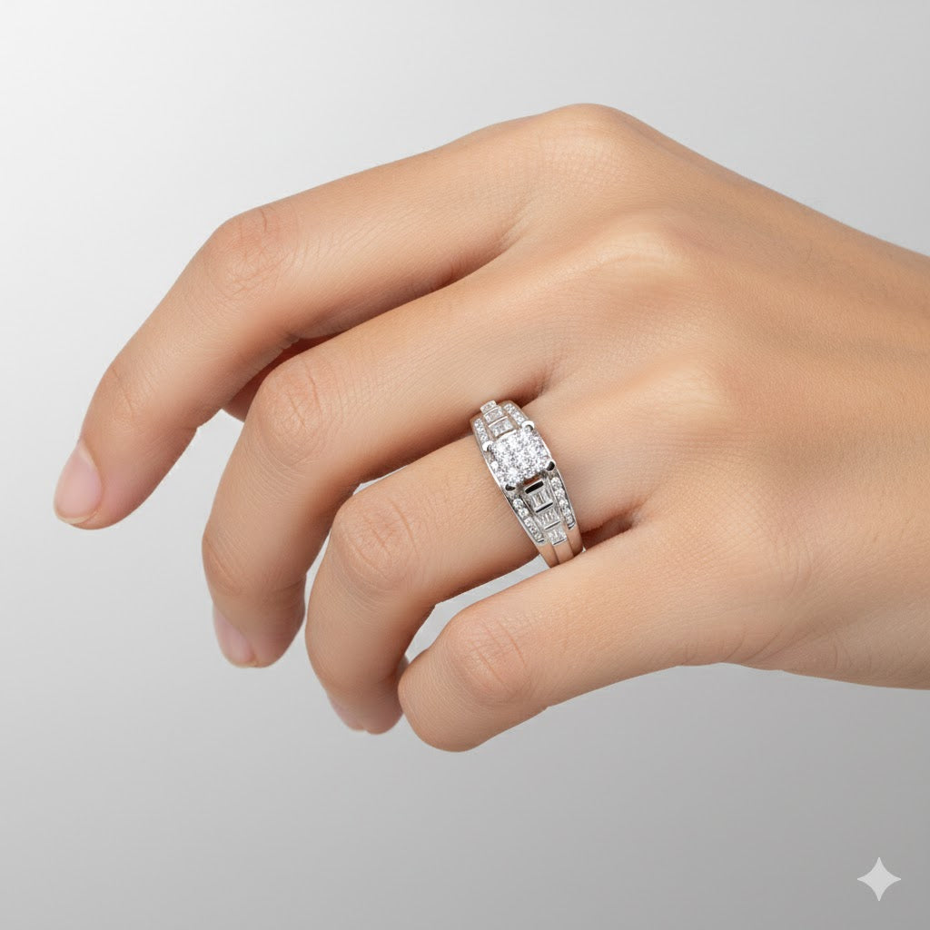A hand with neatly manicured nails wears the 10k White Gold Princess Diamond Engagement Ring 1/2 Cttw, featuring sparkling rectangular and round gemstones, styled like a bridal set against a plain light gray background.