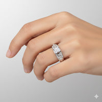 A hand with neatly manicured nails wears the 10k White Gold Princess Diamond Engagement Ring 1/2 Cttw, featuring sparkling rectangular and round gemstones, styled like a bridal set against a plain light gray background.