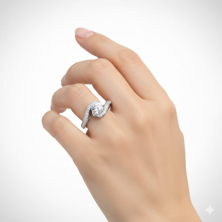 A light-skinned hand wears the Elegant Swirl Halo Lab Diamond Ring – Round Brilliant Stone, showcasing a large round center stone and a curved, stone-encrusted band against a plain white background.