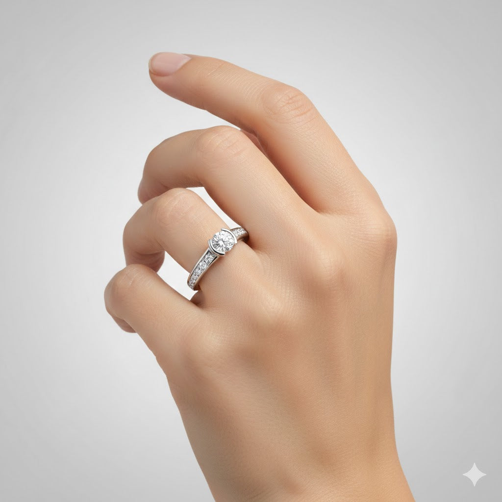 A hand with manicured nails is shown against a light gray background, wearing the Classic Channel-Set Lab Diamond Engagement Ring featuring a round lab diamond center stone and smaller diamonds set along the band.