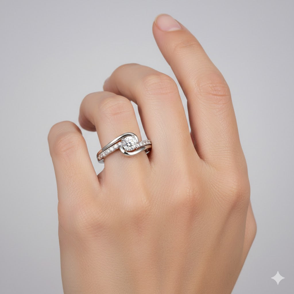 A hand wearing the Swirl Pavé Round-Cut Lab Diamond Engagement Ring, featuring a central round lab diamond and pavé-set side stones, is shown against a plain, light grey background.
