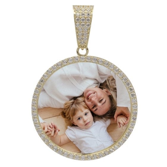 The 10k Solid Gold Picture Pendant with CZ Stones features a round design bordered with sparkling CZs, displaying a photo of a smiling woman and child lying on a wooden floor, holding hands and looking up.