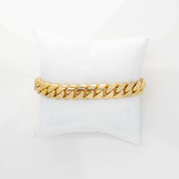 The Cuban Link Bracelet - 11mm Solid Gold is displayed on a white cushion set against a plain white background.