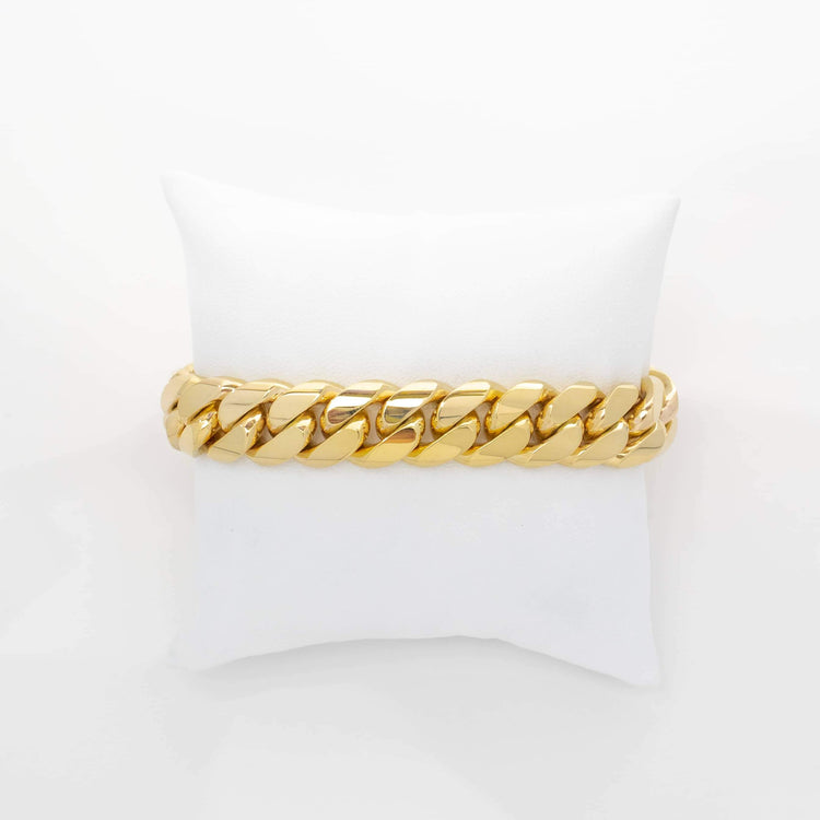 The 14mm Handmade Miami Cuban Link Bracelet in 10K/14K solid gold is displayed on a white fabric cushion against a plain background, highlighting its classic, handcrafted style.