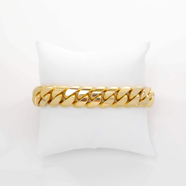 The 15mm Handmade Miami Cuban Link Bracelet in 10K/14K solid gold is displayed on a white cushioned stand and photographed against a plain white background.