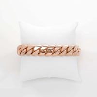 The Cuban Link Bracelet - 15mm Solid Gold rests on a white cushioned pillow, viewed from above against a plain white background.