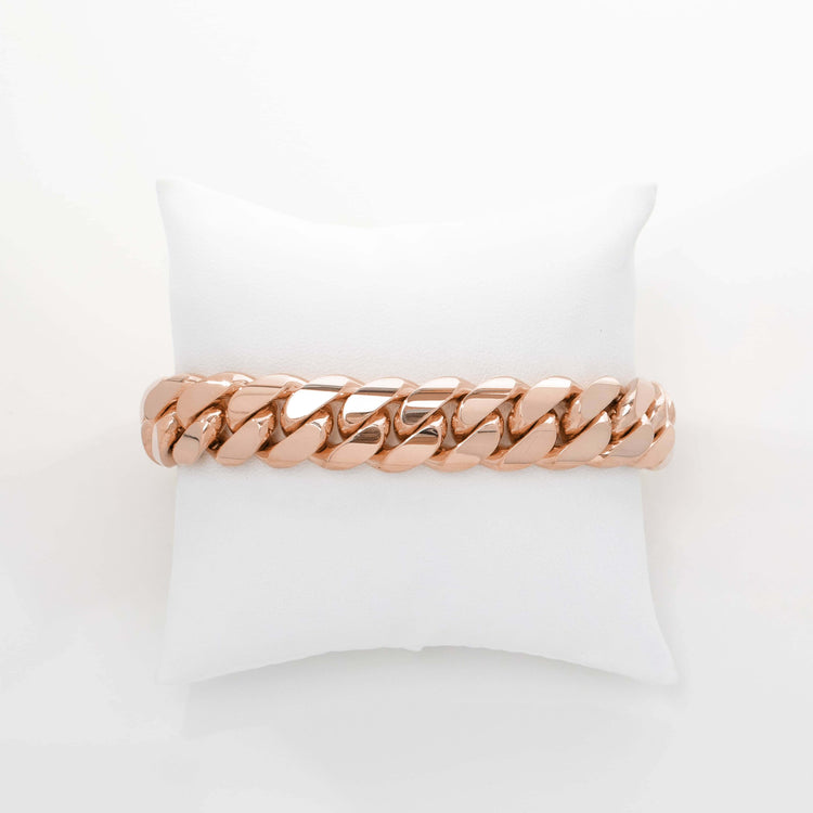 The 15mm Handmade Miami Cuban Link Bracelet in solid 10K or 14K gold is shown resting on a white cushioned pillow, photographed against a plain white background.