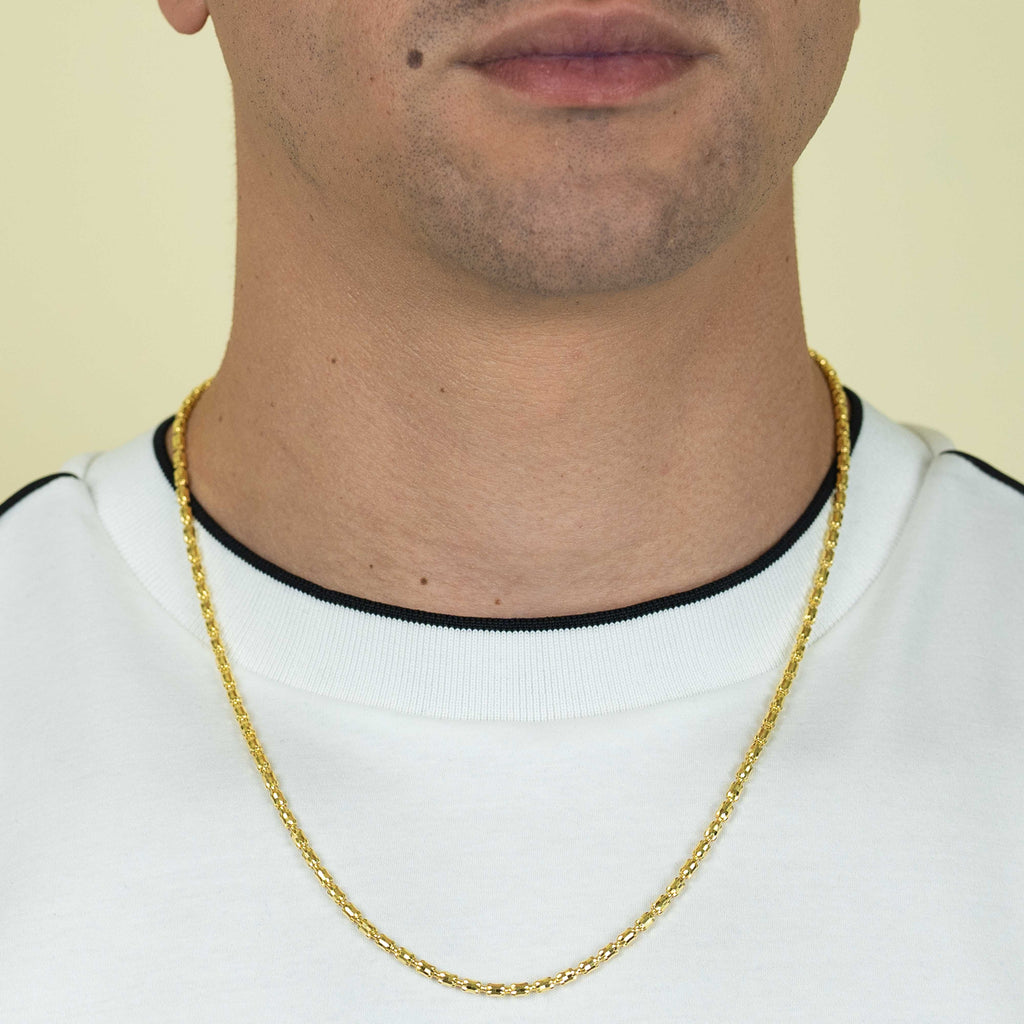 A person is shown from lips to upper chest, wearing a white shirt with black trim and the 3mm Barrel Crystal Chain necklace in 14k gold bonded, against a plain light background.