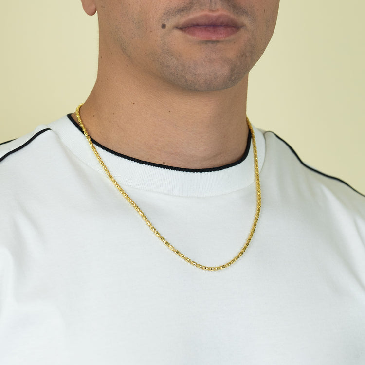 A person wearing a white shirt with black trim and the 3mm Barrel Crystal Chain in 14k Gold Bonded, shown from the shoulders to just above the mouth against a light background.