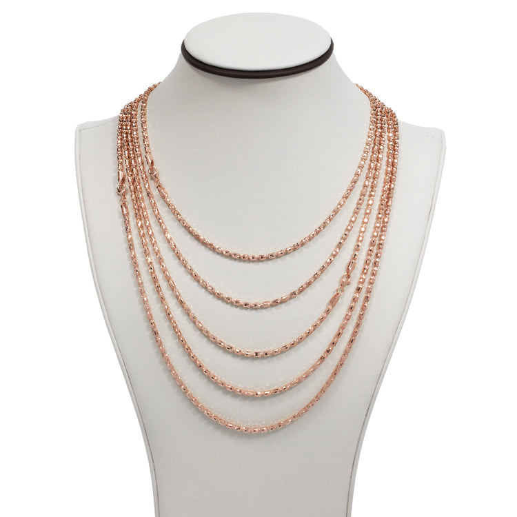 A white jewelry bust showcases the 3mm Barrel Crystal Chain—14k rose gold bonded—featuring seven elegantly draped, multi-layered, interlinked tiers.