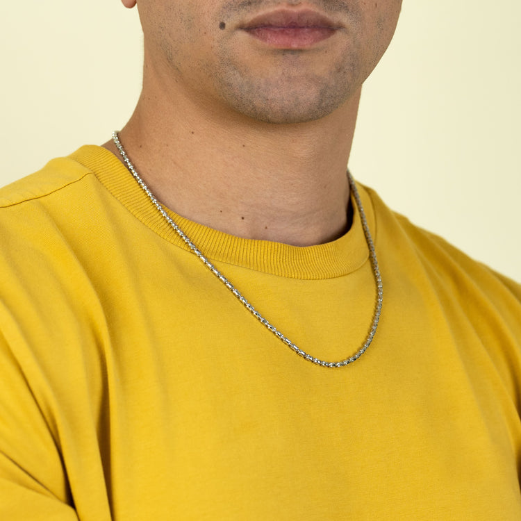 A person in a yellow shirt wears the 3mm Barrel Crystal Chain necklace (925 Silver), shown from the shoulders up against a light background. Only their lower face is visible; their eyes are not shown.