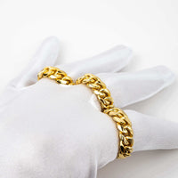 A hand in a white glove displays the 8mm Miami Cuban Link Ring, crafted in solid gold, along with a thick gold chain bracelet against a plain white background.