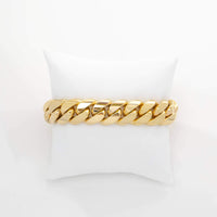 The Cuban Link Bracelet - 16mm Solid Gold is displayed on a white pillow against a plain white background.