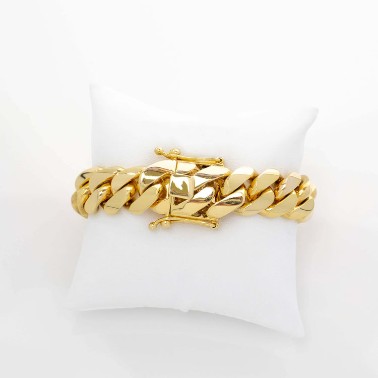The 17mm Handmade Miami Cuban Link Bracelet in 10K/14K solid gold, featuring a box clasp, is showcased on a white cushion against a plain white background.