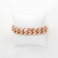 The Cuban Link Bracelet - 18mm Solid Gold shines brightly atop a white cushioned pillow, set against a plain white background.