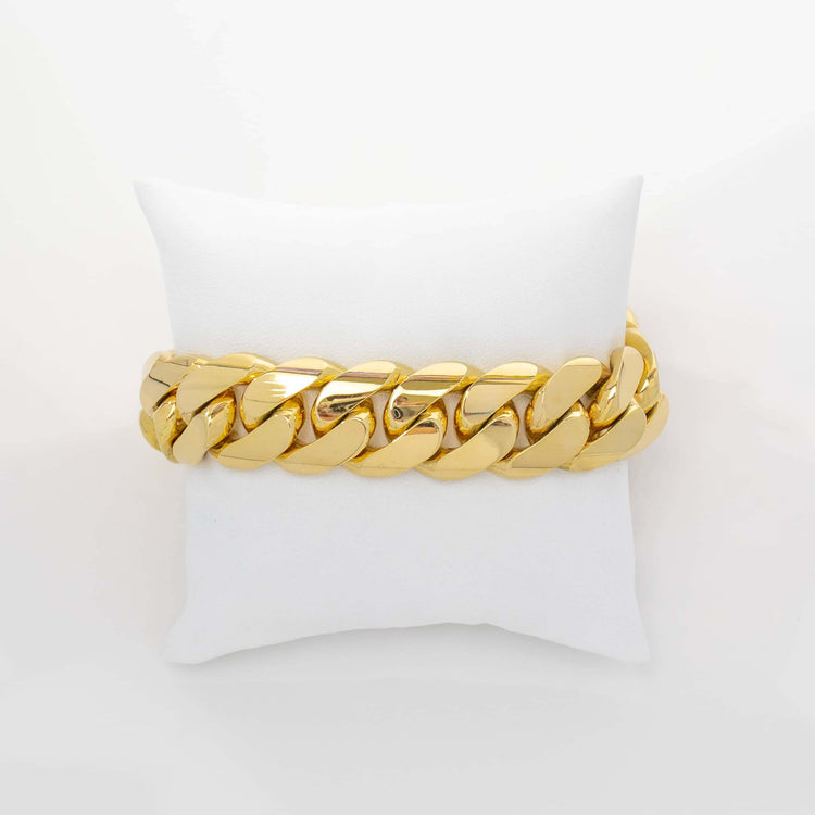 The 19mm Handmade Miami Cuban Link Bracelet in 10K or 14K solid gold is displayed on a white cushion against a light background, showcasing its thick, shiny links.