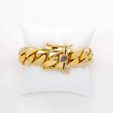 The 20mm Handmade Miami Cuban Link Bracelet in 10K/14K solid gold features a chunky design and square clasp, showcased on a white cushion with a plain white background.