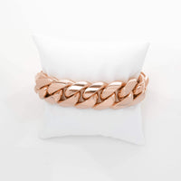 The Cuban Link Bracelet - 20mm Solid Gold, a bold luxury jewelry piece, is shown on a white cushion against a plain white background.