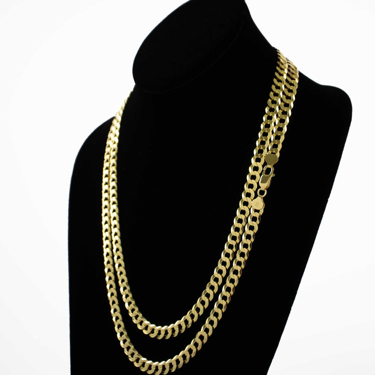A black velvet jewelry bust displays the Curb Link Chain - 8mm 14k Gold Bonded, layered with two gold chain necklaces, all set against a clean white background.