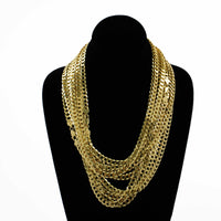 A black display stand shows off layered gold necklaces, featuring the Curb Link Chain - 8mm 14k Gold Bonded and other gold bonded styles, all set against a white background.