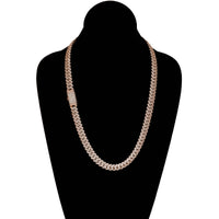 The Diamond Cuban Link Chain – 8mm-17.5mm Solid Rose Gold is shown on a black velvet bust, featuring a rectangular clasp adorned with small, sparkling diamonds.